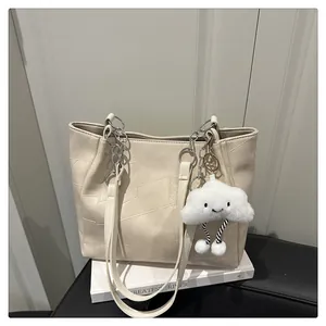 Detail of cream tote bag with geometric stitching and plush cloud pendant charm