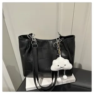 Detail of a black textured tote bag with silver chain and white cloud plush charm