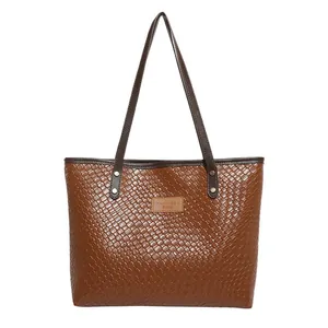 Brown woven tote bag for women with fine texture and leather straps on white background