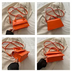 Detail view of orange mini crossbody bag with gold logo from multiple angles