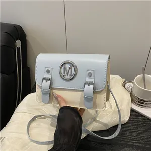 Sac bandoulière bicolore chic avec logo M en métal posé sur un support en tissu doux