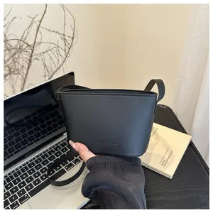 Detail of minimalist black matte bucket bag with embossed logo and slim shoulder strap