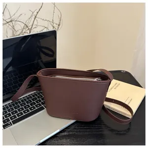 Close-up of brown matte leather crossbody bag with zipper and embossed FANYISSA logo