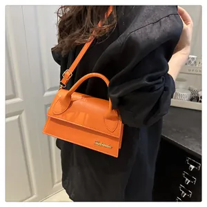 Detailed macro view of the vibrant orange PU leather finish and gold Sabrina logo