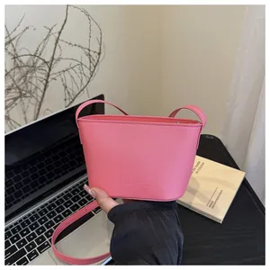 Detailed shot of pink leather bucket bag with Fanyissa logo in a stylish workspace setup