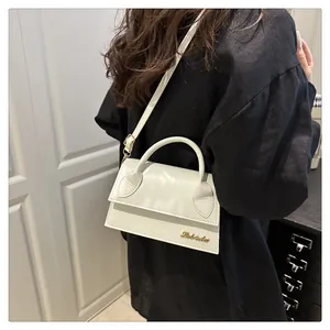 Detail of white mini flap bag with gold Bebalu logo and matte PU leather texture