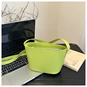 Detail of neon green bucket bag with FANYISSA logo next to a laptop computer