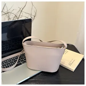 Detail of beige leather bucket bag with FANYISSA logo next to a laptop on a desk