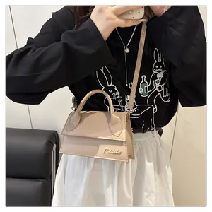 Detail view of beige mini trapezoid handbag with gold logo and detachable shoulder strap
