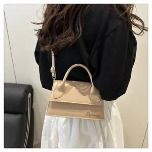 Detail view of the beige trapezoid handbag showing the curved handle and gold logo