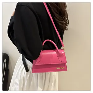 Model wearing a vibrant rose pink mini crossbody bag with a curved handle and gold logo