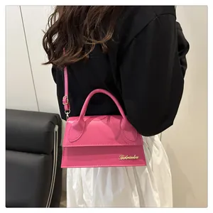 Detailed view of the mini fuchsia leather crossbody bag with top handle and gold logo