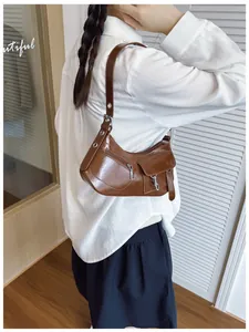 Brown semi-circle underarm bag with biker style zippers and metallic buckle details
