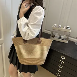 Woven straw tote bag with striped pattern and faux leather straps for summer beach travel