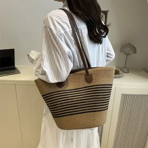 Large woven straw tote bag with black stripes and brown leather straps for beach or daily use