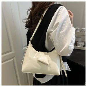 Detail of cream-colored shoulder bag with geometric folding flap and decorative strap