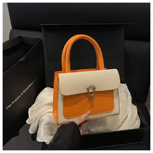Detail of a chic orange and beige woven handbag presented in a luxury gift box