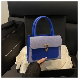 Detail of luxury square bag with blue striped fabric, snakehead lock and premium box