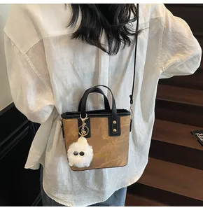 Mini tote bag with faux leather finish and plush pendant charm worn on a shoulder