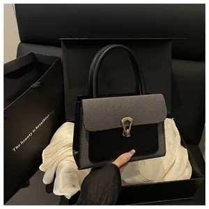 Detail of elegant black patchwork square bag with gold lock and premium gift packaging