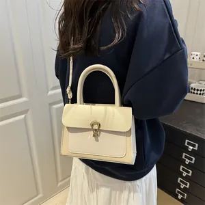 Elegant beige woven texture square handbag with gold horseshoe buckle worn as crossbody bag