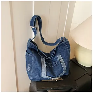 Detail of vintage distressed denim tote bag with frayed holes and adjustable strap