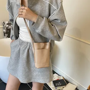 Piccola borsa a tracolla beige in pelle martellata per cellulare indossata con look casual