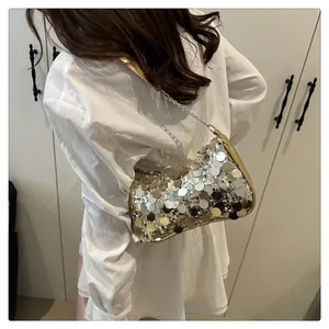 Detalle del bolso de lentejuelas plateadas con borde dorado y cadena sobre camisa