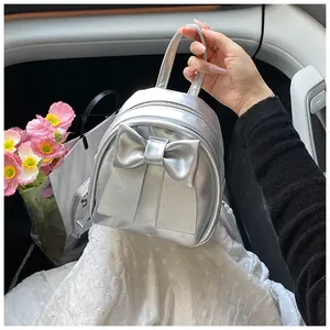 Close-up of metallic silver mini backpack featuring a large bow and sleek zipper detail