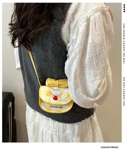 Détail du sac bandoulière vichy jaune avec chien de dessin animé et nœud sur le côté