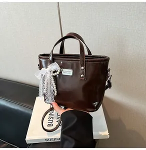 Detailed macro of brown glossy patent leather bag with lace bow and pearl charm
