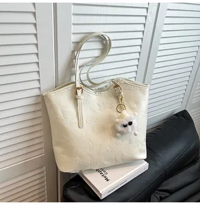 Detailed view of white embossed tote bag with floral patterns and a plush charm accessory
