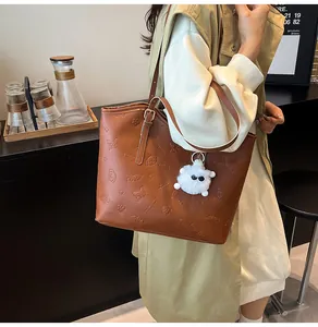 Brown vintage tote bag detail with embossed puppy floral pattern and plush monster charm