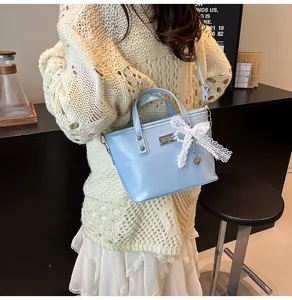 Detail of light blue bucket bag with white lace bow and heart-shaped metal pendant