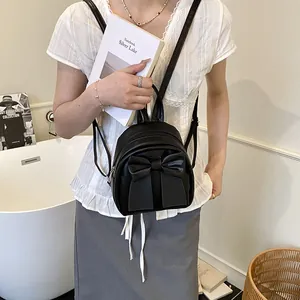 Black mini backpack for women featuring a large decorative bow and matte faux leather finish
