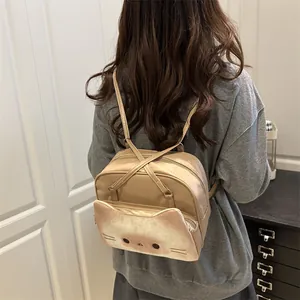 Beige cat-themed backpack with cute ear details and feline face print shown on model