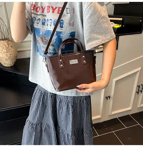 Brown patent leather bucket bag with silver metal plaque and adjustable strap for women