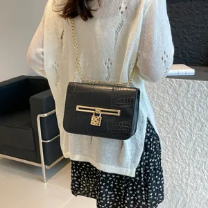 Black crocodile pattern shoulder bag with gold chain and heart lock detail on model