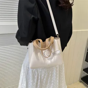 Chic beige PU leather bucket bag with top handle and cute rabbit charm for daily commuting