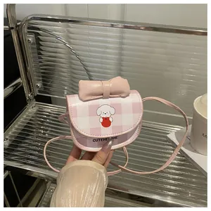 Détail d'un petit sac à bandoulière à carreaux roses avec nœud et motif de chiot
