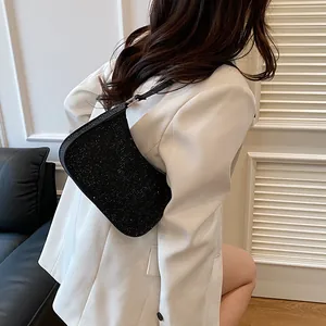 Elegant black rhinestone hobo shoulder bag shown on model wearing a white blazer