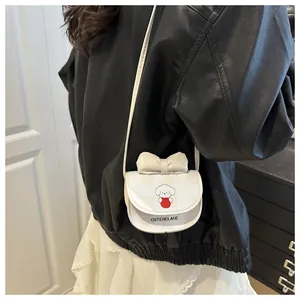 Vue détaillée du sac bandoulière crème avec nœud et chiot sur une veste noire