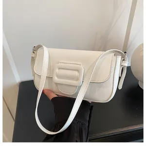 Close-up of white minimalist faux leather baguette bag with large square buckle flap detail