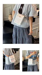 Détails du sac seau bandoulière en cuir blanc avec rabat géométrique et logo doré