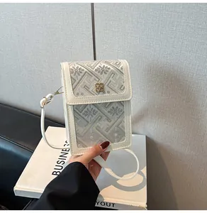 Détail du tissu brodé floral et du fermoir métallique doré sur le sac seau blanc cassé