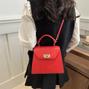 Elegant red leather handbag with gold metal lock on a model in a minimalist setting