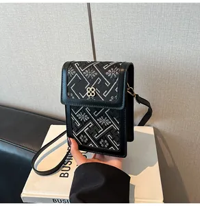 Détail du motif tissé et de la boucle fleur dorée sur un sac seau noir chic