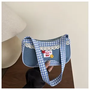 Detail of blue plaid patchwork shoulder bag with lace trim and cherry embroidery