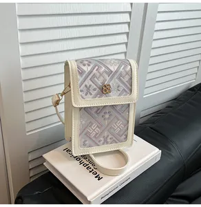 Détail du motif floral brodé et de la boucle dorée sur ce sac seau en crème