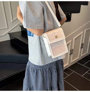 Close-up of geometric diamond embroidery and gold floral hardware on white bucket bag
